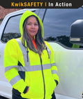 Woman wearing ROGUE Safety Jacket for Women With Class 3 ANSI Reflective Hi Vis Fleece Hoodie Yellow Small Size next to truck.