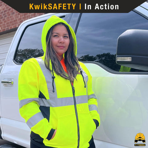 Woman wearing ROGUE Safety Jacket for Women With Class 3 ANSI Reflective Hi Vis Fleece Hoodie Yellow Small Size next to truck.