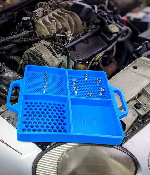 Silicone Fastener Tray For Bolts, Nuts, And Bits With Handy Handle placed on car engine bay showing storage compartments.