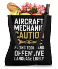 Caution Flying Tools Tote Bag For Aircraft Mechanic And Aviation Tech filled with flowers, wine, bread, and fruit.