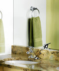 Chateau Chrome One-Handle Low Arc Centerset Bathroom Sink Faucet With Drain Assembly on marble counter next to green towel