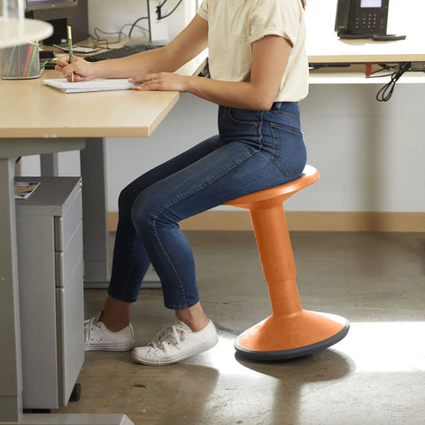 Person seated on SitWell Wobble Stool With Adjustable Height For Active Seating In Classrooms And Home Learning, orange.