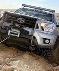 4x4 vehicle using winch to maneuver through sandy terrain with rugged tires visible, showcasing outdoor adventure capabilities.