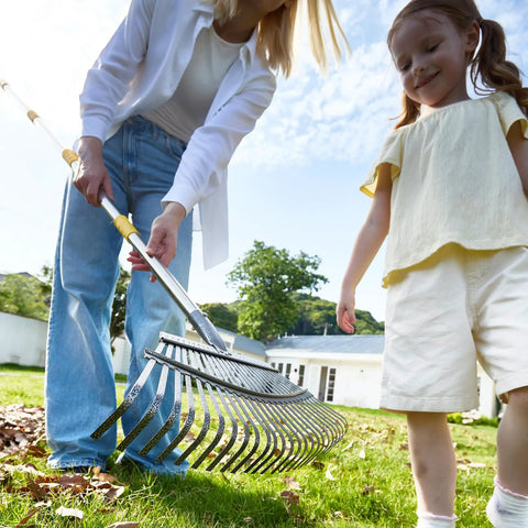 Person using Heavy Duty Wide Garden Leaf Rake With Adjustable Long Handle For Yard And Lawn Cleanup, Ergonomic Rake Head With 25 Tines, Telescopes From Roughly 39 To 69 Inches, Tackles Leaves Fast And Easy, Easy Assembly on a sunny lawn.