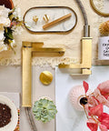 Gold Vessel Sink Faucet in Brushed Gold Finish, Tall Single Hole Bathroom Faucet on table with decor items and flowers