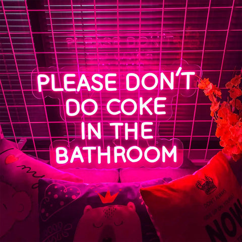 Please Don't Do Coke In The Bathroom LED neon sign pink glow 40x26 cm for indoor bedroom wall decor with pillows on a grid background