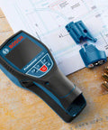 Road Ready 5 In 1 Wall Scanner And Electronic Stud Sensor with LCD screen on wood surface, next to blue attachments and batteries.