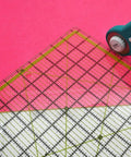 Game Changer Clear Acrylic Quilting Ruler Set for Precise Cutting on pink fabric with rotary cutter