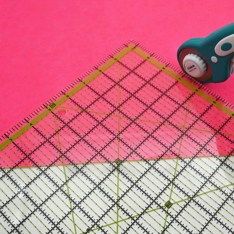 Game Changer Clear Acrylic Quilting Ruler Set for Precise Cutting on pink fabric with rotary cutter