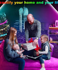 Family in living room with LED Strip Lights For Bedroom With Music Sync, App Control And Remote, Color Changing RGB Light Strips For Room Decor, Party Ambience, 30 Foot, Easy Install, Self Adhesive Tape, Flexible Setup, Great For Dorm Rooms, Gaming Setups And Movie Nights; father giving gift to daughter, colorful lighting on Christmas tree in background