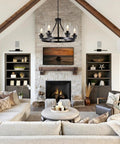 Six Light Farmhouse Wagon Wheel Chandelier Pendant Light Fixture In Matte Black hangs above living room with stone fireplace