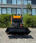 Front view of Beast Mode Skid Steer Loader with reinforced frame, showcased against backdrop of green plants and large windows.