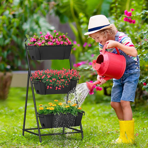 Child watering a space saving 3 tier raised garden bed vertical planter with drainage holes on patio with colorful flowers