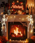 Two 15.7 Inch Hanging Skeleton Decorations With Full Body Posed Joints by a fireplace with pumpkins and candles, spooky Halloween decor