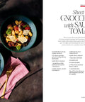 Open cookbook showing 'Sheet Pan Gnocchi with Sausage and Tomatoes' recipe from Over 100 Family Favorite Recipes You Can Make At Home For Busy Nights And Cozy Weekends From Angela Kinsey And Joshua Snyder A No Fuss Weeknight Friendly Cookbook For Real Life Cooking.