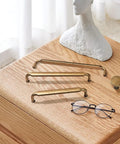 Antique Brass Zinc Alloy Cabinet Pulls 12 Pack Three And Three Quarters Inch Hole Centers Drawer Handles on wooden surface