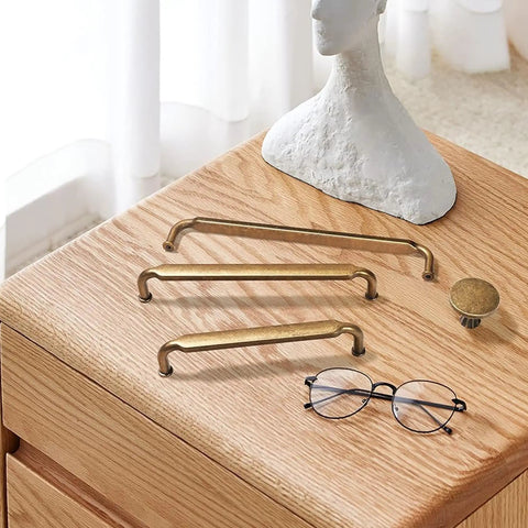 Antique Brass Zinc Alloy Cabinet Pulls 12 Pack Three And Three Quarters Inch Hole Centers Drawer Handles on wooden surface