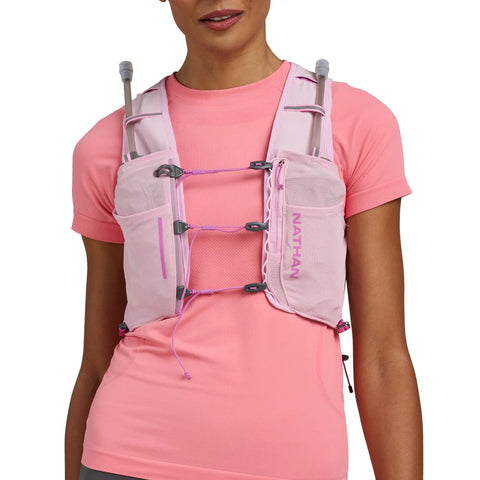 Close-up of a woman wearing the Pinnacle Pro 6L Women's Hydration Vest With Second Skin Fit In Light Pink Fuchsia, showing front pockets.