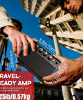 Hands holding a 10W Portable Guitar Amp With Rechargeable Battery, showing measurements against urban background, Travel Ready.