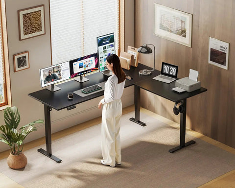 Woman working at 63 Inch Reversible L Shaped Electric Standing Desk Height Adjustable Corner Desk for Home Office, black color
