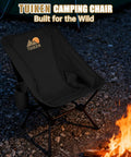 Ultralight Backpacking Camping Chair With Cup Holder And Storage Bag in deep black near campfire, portable and compact.