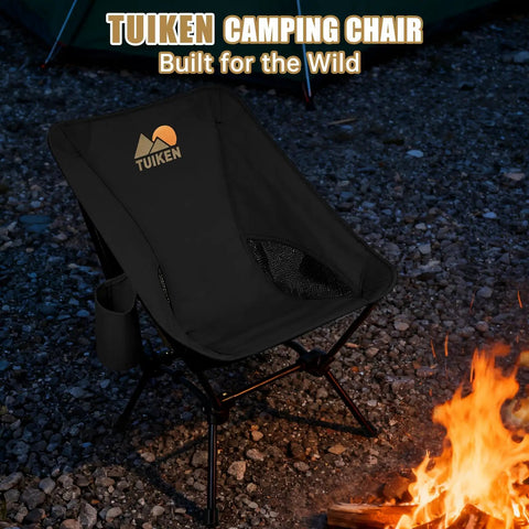 Ultralight Backpacking Camping Chair With Cup Holder And Storage Bag in deep black near campfire, portable and compact.