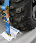 Built Tough To Keep Your Rig Locked Down With Heavy Duty E Track Wheel Chock Tie Down Kit Featuring Two 2 X 6 5 Foot Ratchet Straps And Four Powder Coated Chocks For Safely Hauling ATVs Or Mowers, showing tire secured with blue ratchet strap.