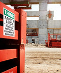 Construction site with 'Think Safety First' sign emphasizing mandatory personal protective equipment.