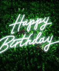 Happy Birthday dimmable LED neon sign on lush green backdrop, 23 inch wall decor with 3 brightness levels for parties.