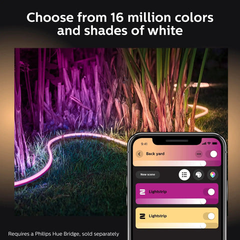 Outdoor Seven Foot Smart LED Light Strip With Color Changing Ambiance Weatherproof For Decks Railings Steps Pathways And Landscaping Control Via Hue Bridge App And Voice Assistants Like Alexa Google Assistant And Apple HomeKit lit in vibrant colors next to plants with mobile app interface displayed