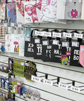 Retail display with Heavy Duty 8 Inch Slatwall Double Bar Hooks Black 50 Pack showcasing bags and goods.