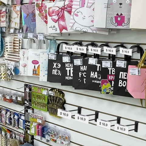 Retail display with Heavy Duty 8 Inch Slatwall Double Bar Hooks Black 50 Pack showcasing bags and goods.