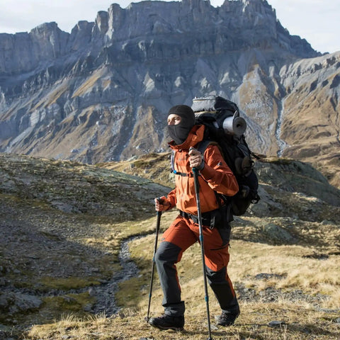 Person hiking in mountains wearing Cooling Balaclava Face Mask With Merino Wool And Lyocell, using trekking poles.