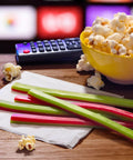 Watermelon Berry Collision Ropes Candy Soft And Chewy 9 Oz Bag with tart filling next to popcorn, remote, and TV screen background