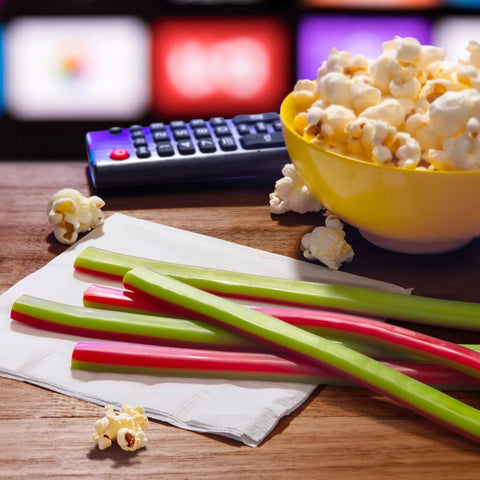 Watermelon Berry Collision Ropes Candy Soft And Chewy 9 Oz Bag with tart filling next to popcorn, remote, and TV screen background