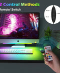 2-In-1 Under Monitor Light Bar For Gaming Setup with remote control in hand, colorful RGB lighting under a computer monitor.