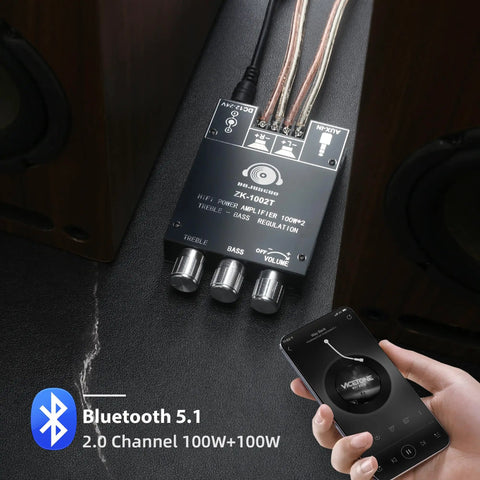 Two Channel 100W Per Side Amplifier Board For DIY Wireless Speakers With Treble And Bass Control DC Nine To Twenty Four Volt Bluetooth And AUX Inputs Password Free Stereo Amp Board placed on a dark surface with a hand holding a phone showing controls.