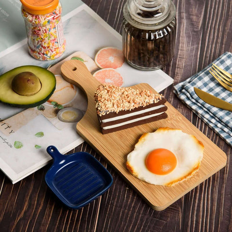 Front view of thick bamboo cutting board, 11x5 in; layered chocolate cake slice and fried egg on top.