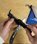 Hands adjusting Four Grit Diamond Sharpening Kit With Whetstone Aligner Quick Edge on wooden table with blue fabric pouch