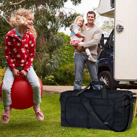 65L Duffle Bag With Shoes Compartment, black foldable travel bag on grass, campervan and family in background, water repellent.