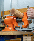 Heavy Duty 5 Inch Multi Purpose Swivel Base Bench Vise With 3 Jaw Styles Rotates 360 Degrees in use on a workbench, holding wood
