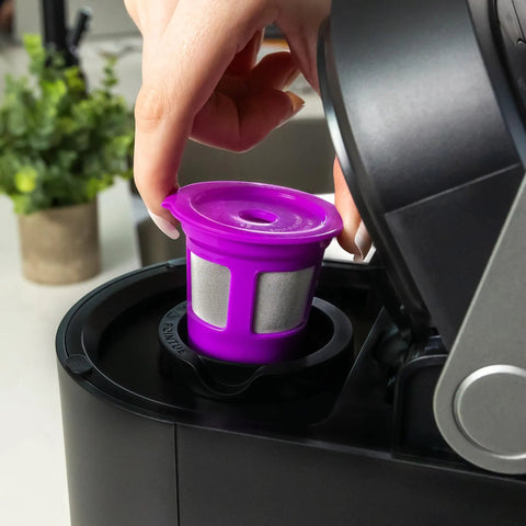 Placing purple reusable K-Cup filter into single cup brewer from Two Item Bundle With Reusable K Cup Coffee Filters Four Pack And EZ Scoop 2 Tbsp Scoop With Integrated Funnel Refillable Pod Capsules For Use With Most Single Cup Brewers Save Money On Every Brew.