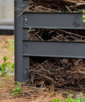 Close-up of a galvanized steel compost bin, showing modular design and removable slats for harvesting compost material.