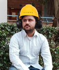 Beefed Up Heavy Duty Safety Hard Hat Earmuffs With Zero Hassle Adjustable Fit And Deep Noise Cancelling Seals For Crews Knocking Out Loud Job Site Projects on a worker wearing a yellow hard hat sitting in greenery.