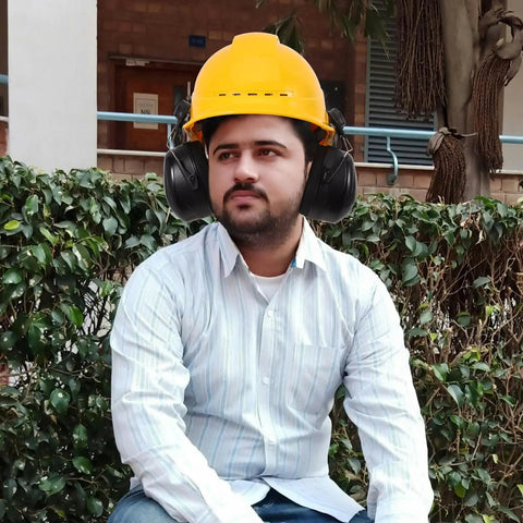 Heavy Duty Earmuffs Built Different Serving Killer Noise Reduction And Hard Hat Compatible Fit Locking Out Industrial Sound For Contractors And Shooters On Site Black Style With Thick Foam Pads, worn by a man outdoors.