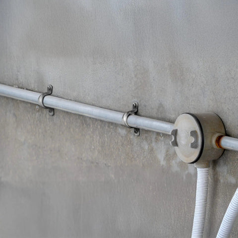 100 Pack 2 Hole 3 Quarter Inch Rigid EMT Pipe Straps, Heavy-Duty Zinc-Plated Steel Clips With Reinforced Rib installed on a wall