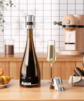 Leak Proof Champagne Stoppers With Stainless Steel Saver And Food Grade Silicone Keep Sparkling Wine Fresh Up To 7 Days Fits Champagne Cava Prosecco And Sparkling Wines Silver 2 Pack shown on a kitchen counter sealing a champagne bottle.