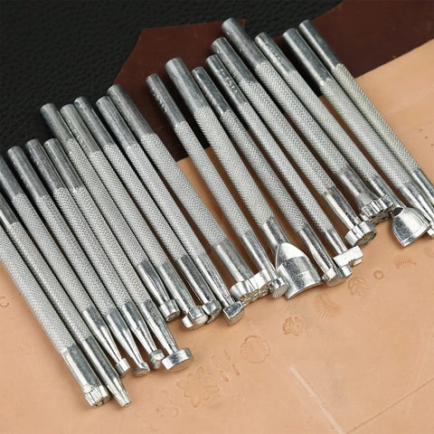 Leather Craft Tools Kit With 20 Leather Stamping Tools and hammer on tan leather surface for DIY leatherwork.