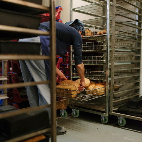 Baker using Heavy Duty Stainless Steel Bracket Casters with 1.5 Inch Wheels on rack, food service application
