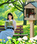Outdoor Wooden Little Library Box For DIY Book Exchange In Neighborhoods And Schools in park with woman reading nearby